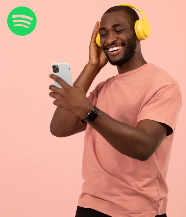 Smiling man streaming music on his phone, representing a boost from buying Spotify monthly listeners