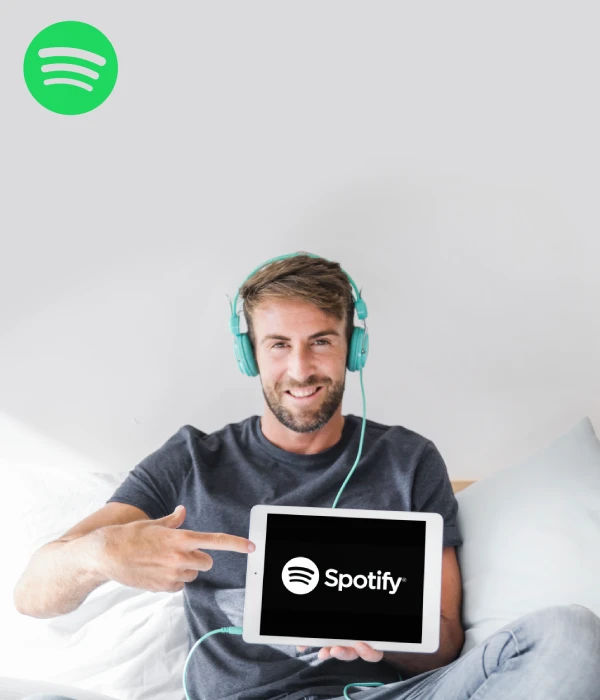 Man proudly pointing at Spotify screen, highlighting how creators can buy real Spotify monthly listeners to grow fast
