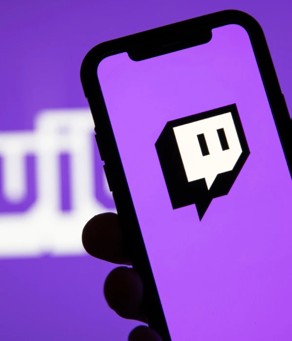 Hand holding a smartphone with the Twitch logo - an easy place to buy Twitch followers when you’re just starting out.